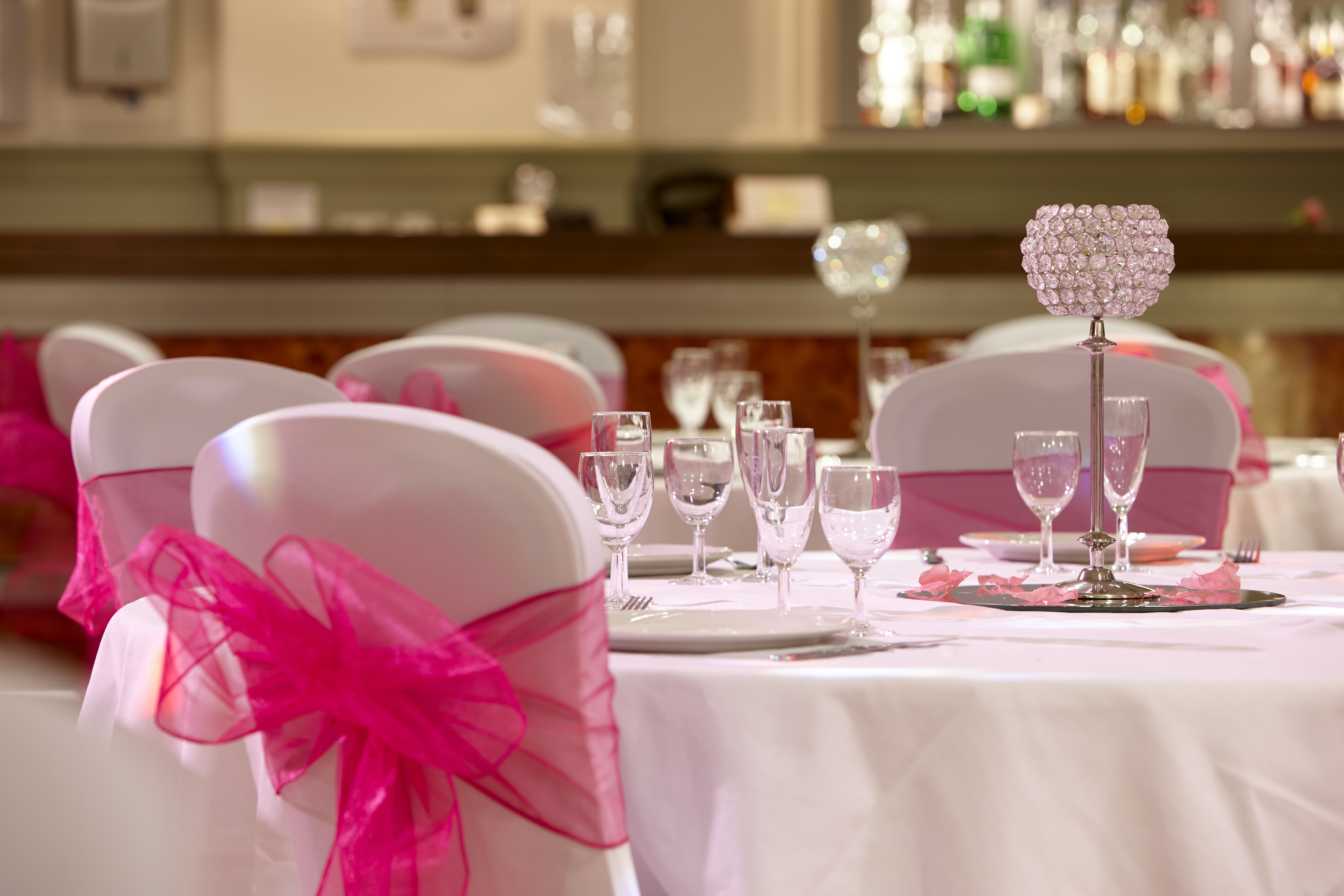 Banquet table close up shot. White chair with pink bow. Set up for wedding.