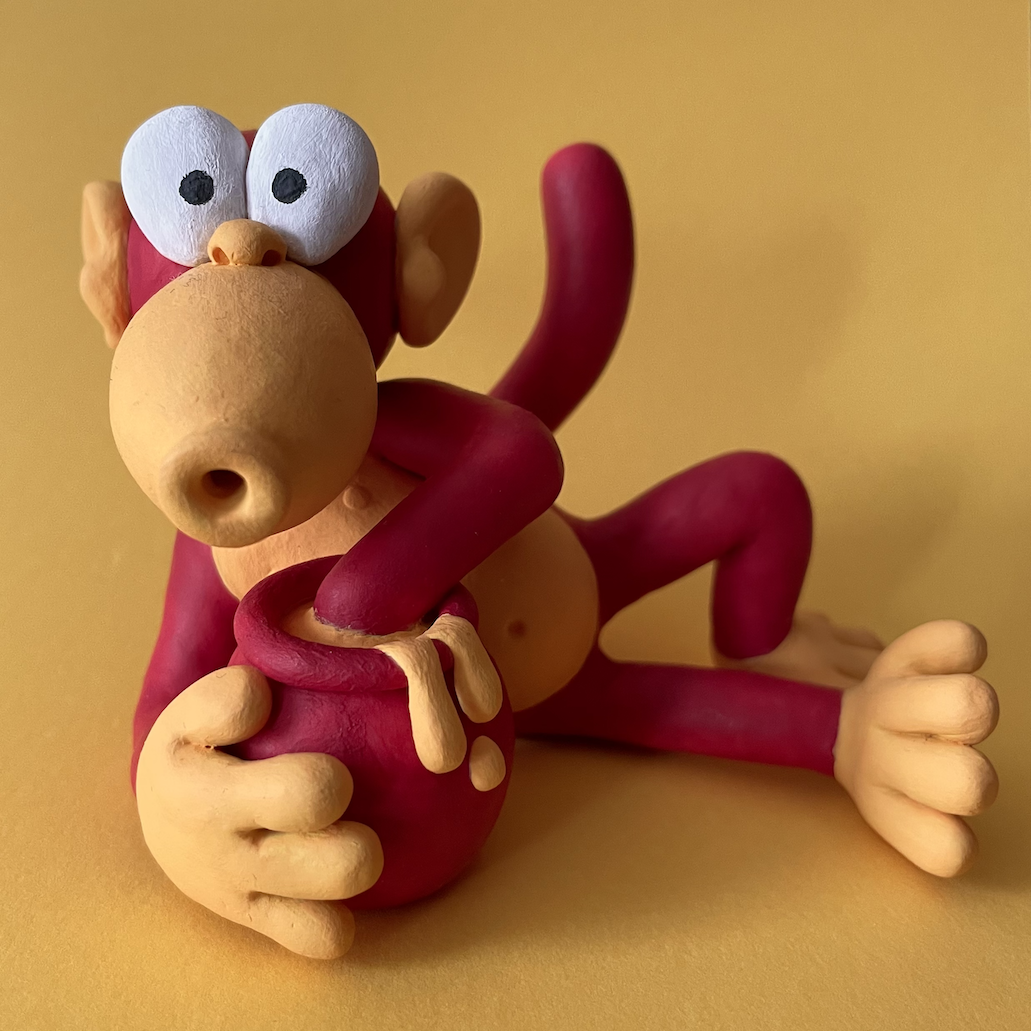 A model of Mêl, the mascot of Mwnci Animation, a red and yellow monkey eating from a jar of honey